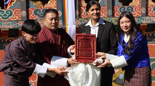 Dr. Bhupinder Kau Aulakh (Resident Coordinator a.i., Mr. Tshering Wangdi (President of Sherubtse College), and members of the Sherubtse UN Club, holding up a woodwork 